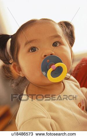 Stock Image - Infant with a pacifier in her mouth. Fotosearch