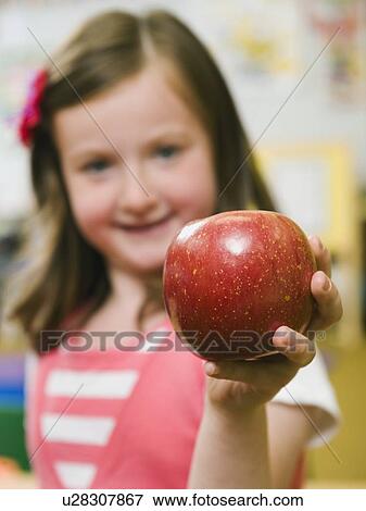 Kindergarten student holding an apple in classroom View Large Photo Image Stock Photo - Kindergarten student holding an apple in classroom. Fotosearch