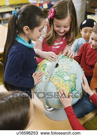 Stock Image - Kindergarten students looking at globe. Fotosearch