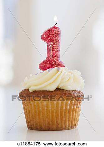 Lit candle on cupcake for first birthday celebration View Large Photo Image Stock Photography - Lit candle on cupcake for first birthday celebration. Fotosearch