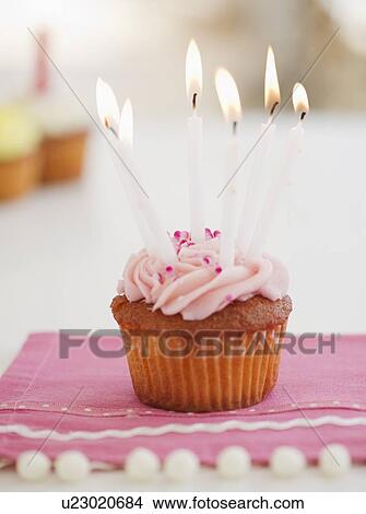 Picture - Lit candles on cupcake. Fotosearch