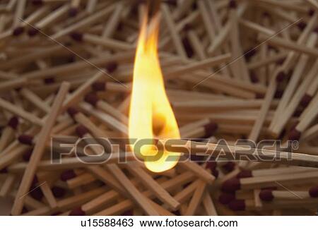 Stock Image - Lit match on top of a pile of wooden matches. Fotosearch
