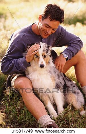 Stock Photo - Man and his dog sitting on grass. Fotosearch