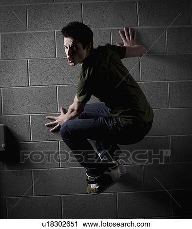 Stock Image - Man climbing a wall. Fotosearch