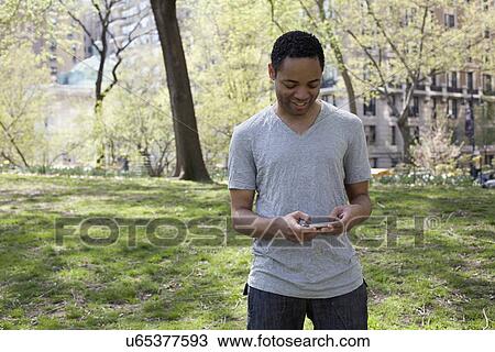 Man in casual clothing texting in park View Large Photo Image Stock Image - Man in casual clothing texting in park. Fotosearch