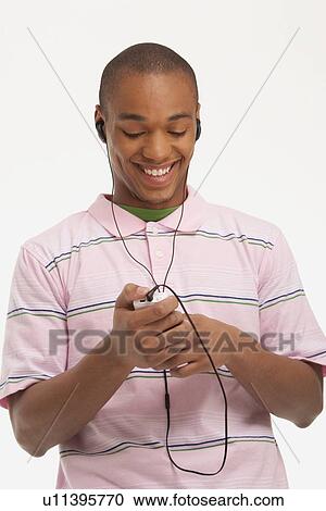 Stock Image - Man listening to music on earphones. Fotosearch