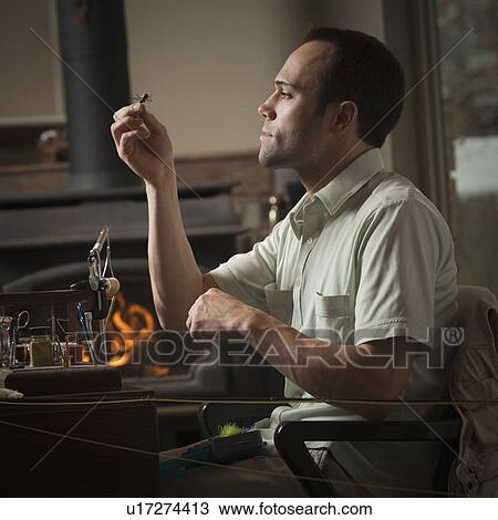 Man looking at fly fishing hook View Large Photo Image Stock Image - Man looking at fly fishing hook. Fotosearch