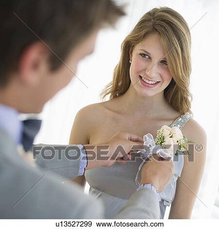 Stock Photo - Man pinning corsage on his date's prom dress. Fotosearch