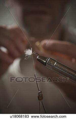 Stock Image - Man repairing fly fishing hook. Fotosearch
