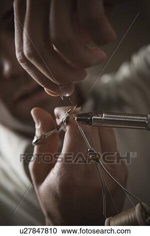 Stock Image - Man repairing fly fishing hook. Fotosearch