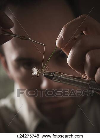 Stock Photo - Man repairing fly fishing hook. Fotosearch