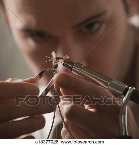 Stock Photograph - Man repairing fly fishing hook. Fotosearch