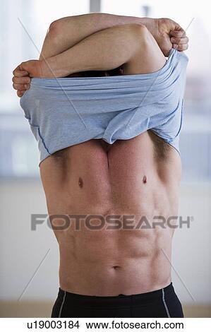 Picture - Man taking off his shirt. Fotosearch