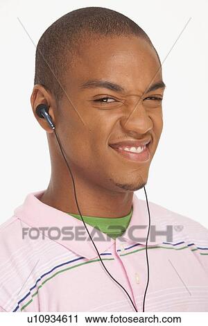 Stock Image - Man wearing earphones making a funny face. Fotosearch
