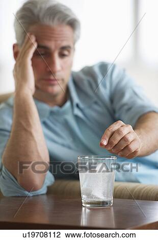 Man with a headache putting medicine in glass of water View Large Photo Image Stock Image - Man with a headache putting medicine in glass of water. Fotosearch