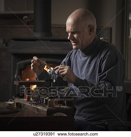 Stock Image - Man working on fly fishing hook. Fotosearch