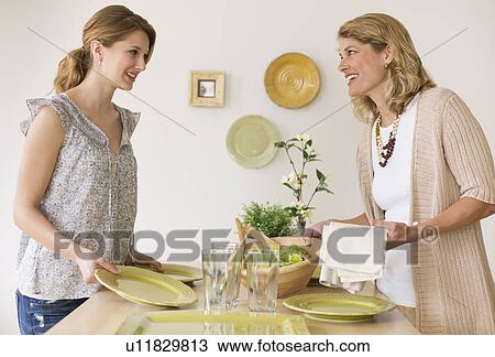 Stock Image - Mother and daughter setting the table. Fotosearch
