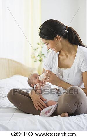 Stock Image - Mother feeding her baby a bottle. Fotosearch