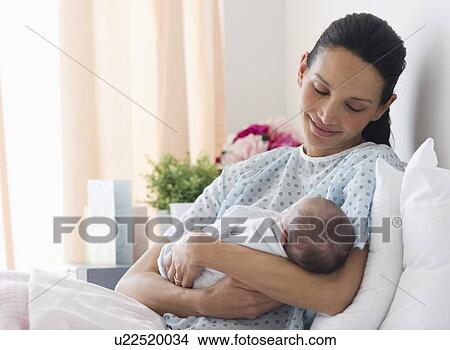 Mother holding newborn baby in hospital bed View Large Photo Image Picture - Mother holding newborn baby in hospital bed. Fotosearch