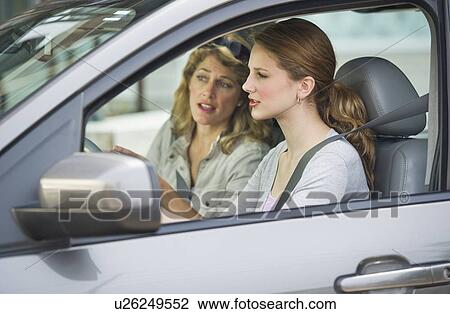Stock Image - Mother teaching her daughter how to drive. Fotosearch
