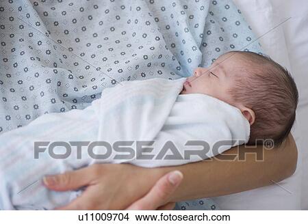 Picture - Newborn baby swaddles in mother's arms. Fotosearch
