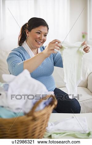 Stock Image - Overweight woman folding clothes. Fotosearch