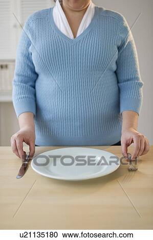 Stock Image - Overweight woman setting the table. Fotosearch