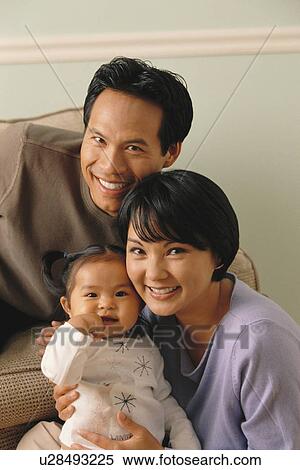 Stock Photography - Parents sitting with their infant daughter. Fotosearch