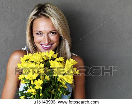 Stock Image - Pretty blond woman holding a bouquet of flowers. Fotosearch