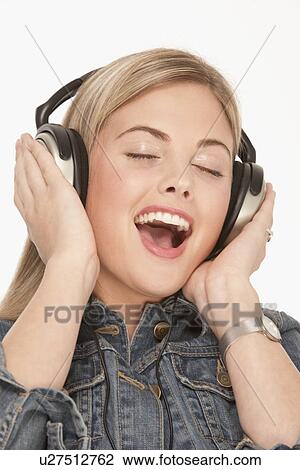 Stock Image - Pretty blond woman singing while wearing headphones. Fotosearch
