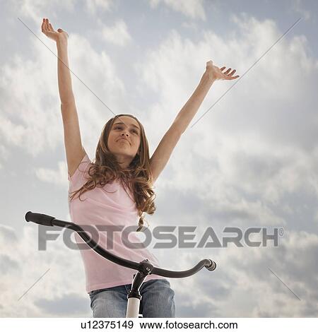 Pretty teenage girl with her arms raised while sitting on bike View Large Photo Image Stock Photo - Pretty teenage girl with her arms raised while sitting on bike. Fotosearch
