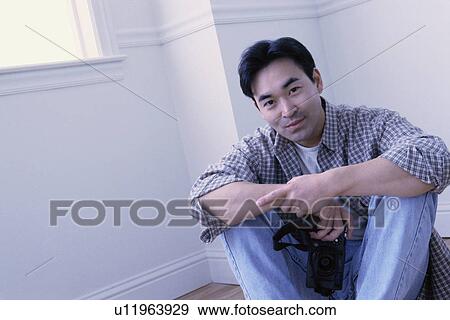 Stock Photo - Relaxed man sitting on the floor in his home. Fotosearch
