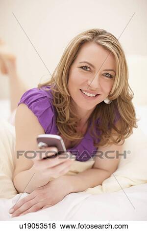 Stock Photo - Relaxed woman holding cell phone. Fotosearch