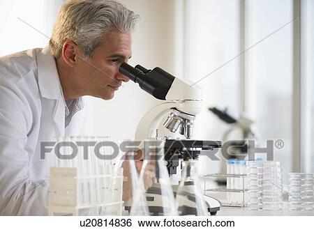 Stock Photograph - Researcher looking through microscope. Fotosearch