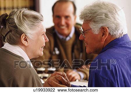 Senior couple sitting at desk across from doctor View Large Photo Image Stock Image - Senior couple sitting at desk across from doctor. Fotosearch