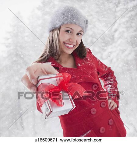 Smiling woman holding out a Christmas gift View Large Photo Image Stock Image - Smiling woman holding out a Christmas gift. Fotosearch
