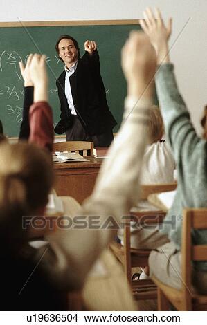 Picture - Students raising their hands in classroom. Fotosearch