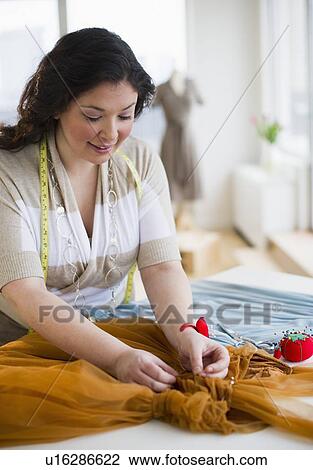 Stock Image - Tailor mending a dress. Fotosearch