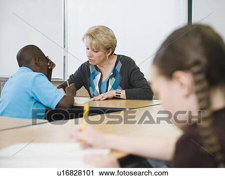 Teacher helping student in elementary school classroom View Large Photo Image Stock Image - Teacher helping student in elementary school classroom. Fotosearch