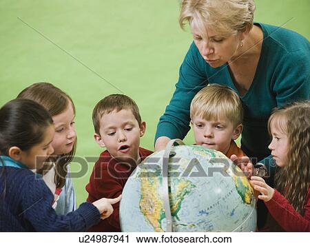 Stock Image - Teacher showing globe to kindergarten students. Fotosearch