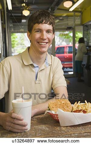 Teenage boy eating at fast food restaurant View Large Photo Image Stock Photo - Teenage boy eating at fast food restaurant. Fotosearch