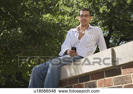 Teenage boy sitting on brick wall View Large Photo Image Stock Photo - Teenage boy sitting on brick wall. Fotosearch
