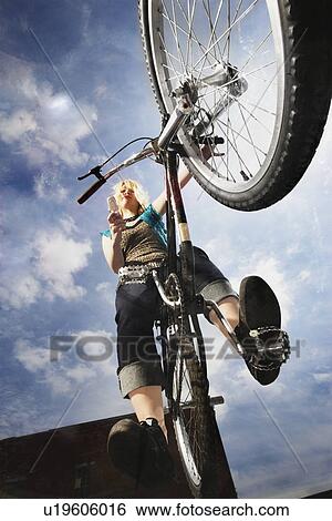 Teenage girl doing a bike trick View Large Photo Image Stock Photograph - Teenage girl doing a bike trick. Fotosearch