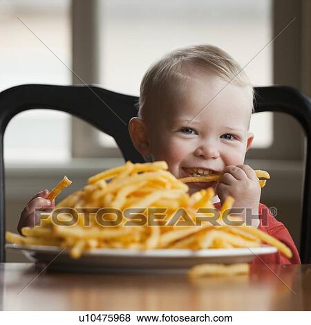 Stock Photo - Toddler eating a large plate of French fries. Fotosearch