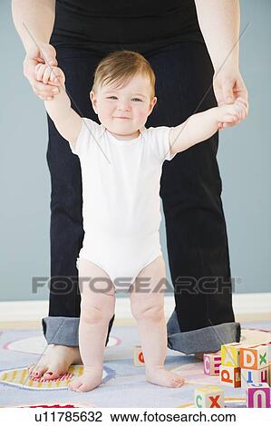 Toddler holding onto mother's hands View Large Photo Image Stock Image - Toddler holding onto mother's hands. Fotosearch