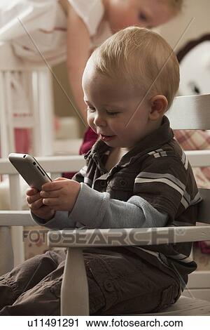 Stock Image - Toddler playing with cell phone. Fotosearch