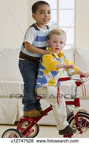 Stock Photo - Two children on a tricycle. Fotosearch