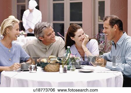 Stock Photograph - Two couples having dinner together on patio of restaurant. Fotosearch
