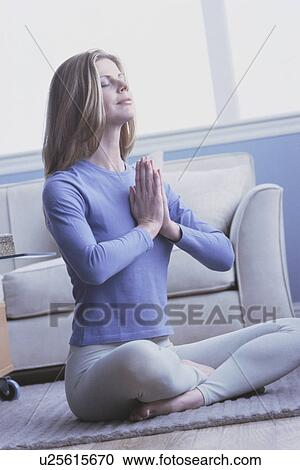 Stock Image - Woman doing yoga in her home. Fotosearch