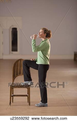 Stock Image - Woman drinking water after exercising. Fotosearch